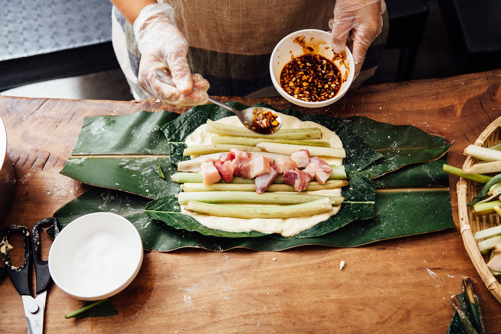 3. 鋪上一層芋頭梗，排上輕鹽醃過的五花肉，再平鋪上芋頭梗，撒上適量的鹽和蒜頭辣椒醬油。