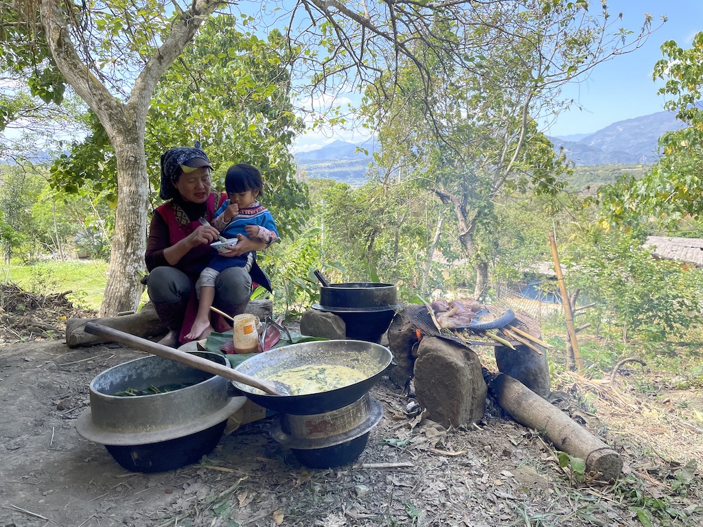 王媽抱著小孫女，一面餵飯、一面用族語說今天煮了哪些料理。